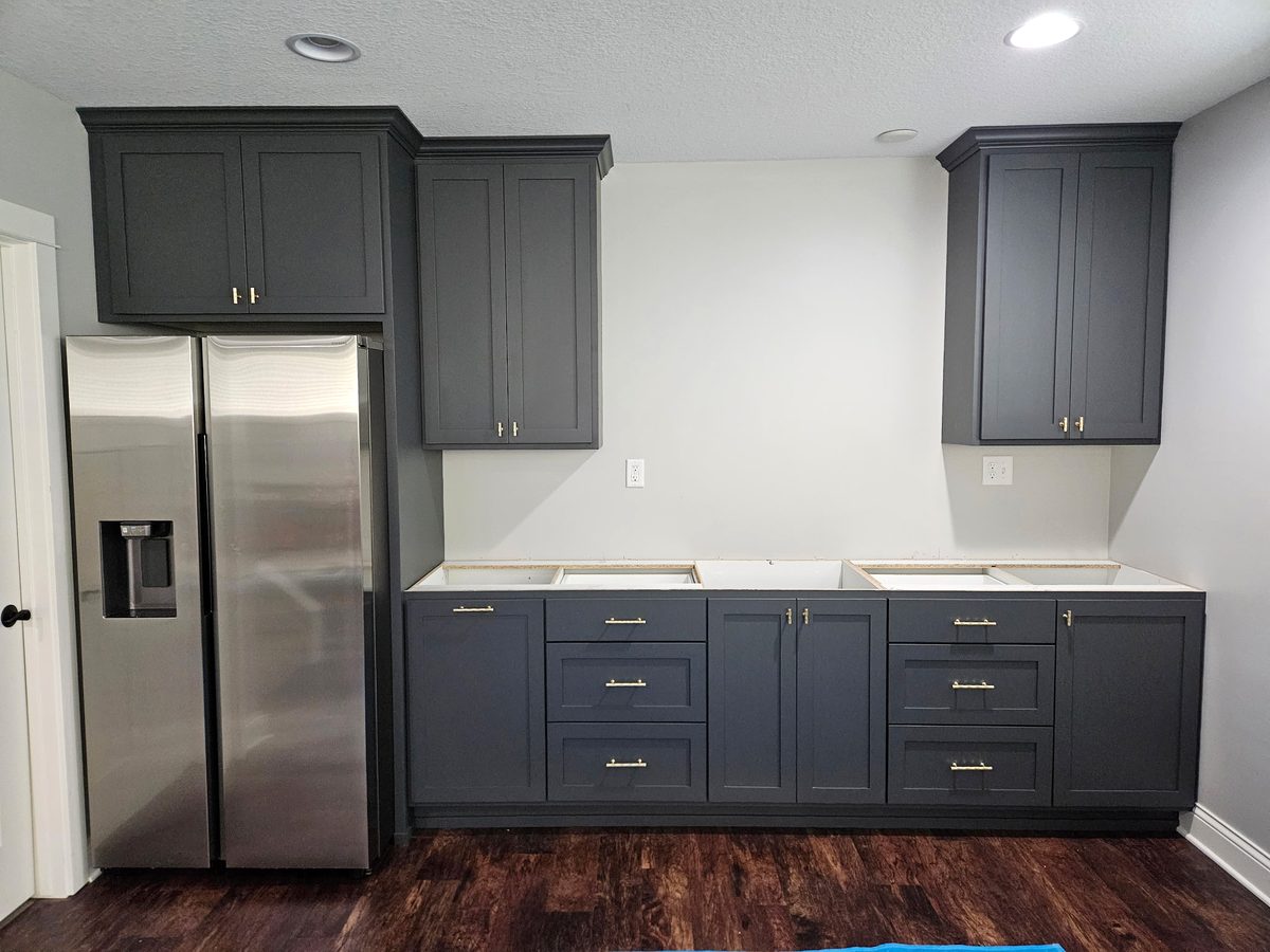 Charcoal shaker cabinets with brass pulls, stepped crown and a cabinet over the refrigerator