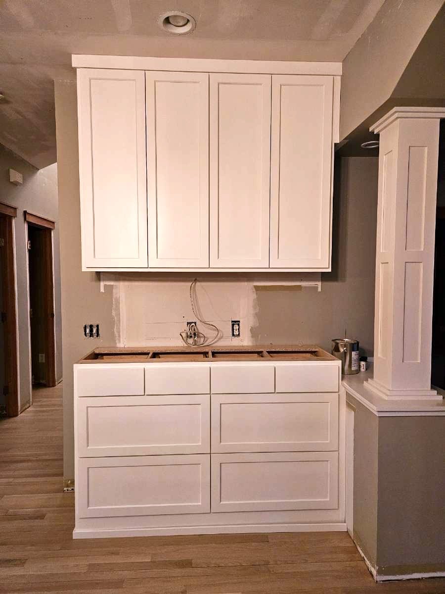 White built-in hutch with four tall upper doors over eight drawers, awaiting its countertop