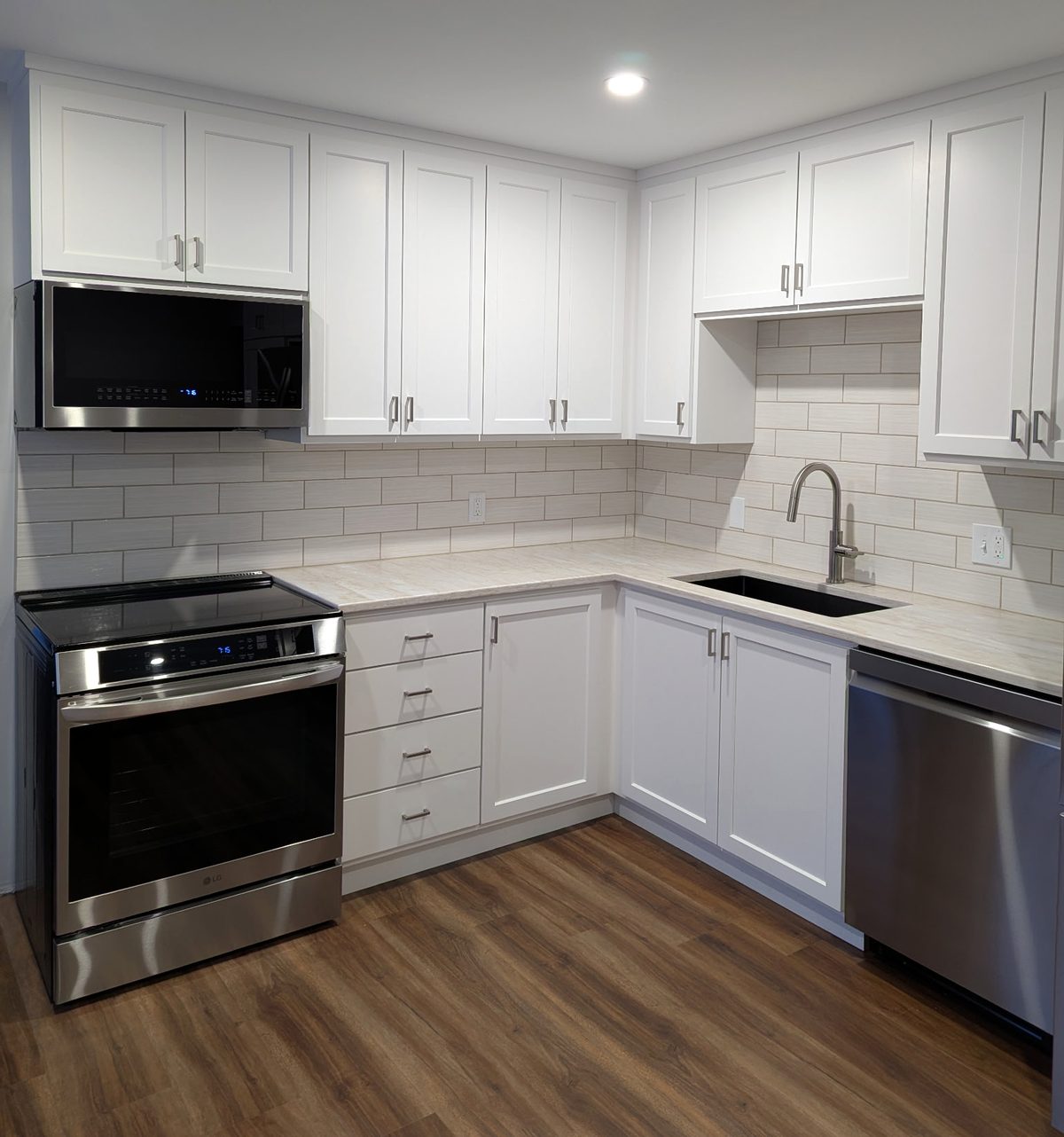 White shaker kitchen cabinets built to the ceiling, with a four-drawer stack beside the range and an undermount sink